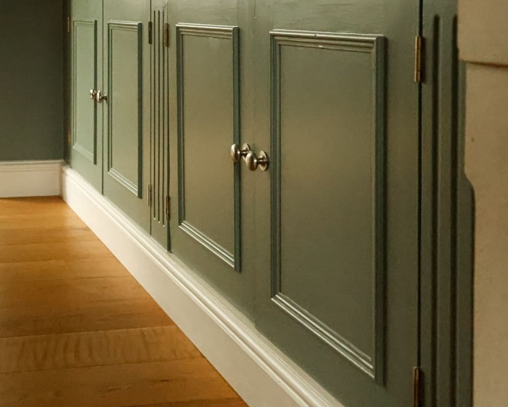 The same kitchen cabinets after painting, finished in a rich sage green